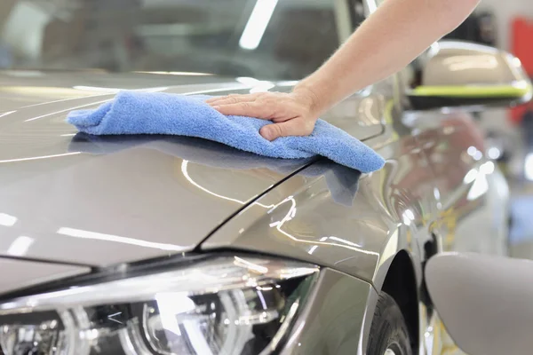 Man hand torka huva av bilen med microfiber tyg närbild — Stockfoto