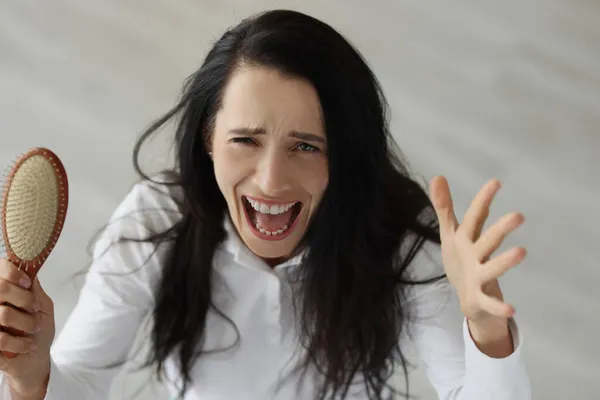 Vrouw met lang haar schreeuwen en houden kam in haar handen — Stockfoto