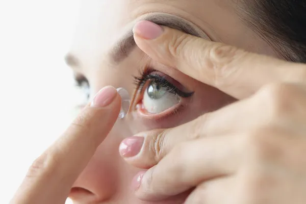 Ung kvinna sätter kontaktlinser i ögat med finger närbild — Stockfoto