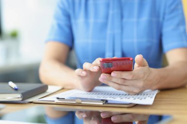 Kadınların elindeki modern akıllı telefon ve iş yerindeki iş grafikleri