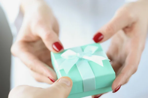 En las manos de la mujer es pequeña caja de regalo de color turquesa con arco —  Fotos de Stock