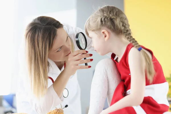 Oftalmolog genomför medicinsk undersökning av flicka öga genom förstoring glas — Stockfoto