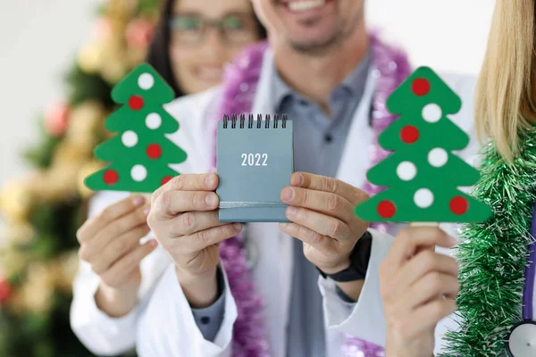 El equipo de los médicos tiene el calendario para 2022 contra el fondo del árbol de Año Nuevo — Foto de Stock