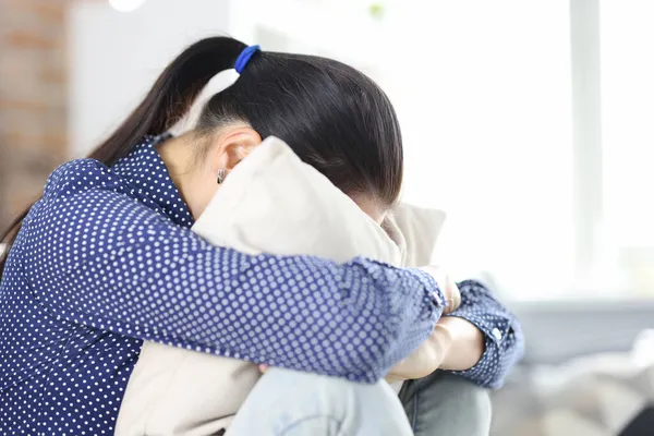 Donna triste si siede sul divano nascondendo faccia in primo piano cuscino — Foto Stock