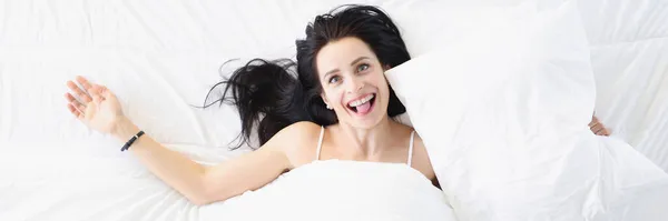 Jovem mulher feliz deitada na cama e mostrando língua vista superior — Fotografia de Stock