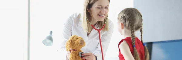 Kinderärztin zeigt kleinem Mädchen am Beispiel von Spielzeug, wie man Stethoskop bedient — Stockfoto