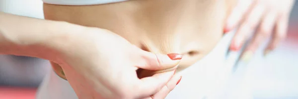 Žena tahá kůži na břicho a předvádí krásné břišní svaly — Stock fotografie