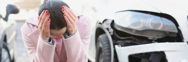 Empörte junge Frau sitzt mit gesenktem Kopf neben Autowrack — Stockfoto