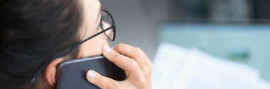 İş kadını akıllı telefondan konuşuyor ve şirket sorunlarını çözen belgeleri okuyor.