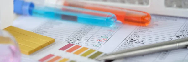 Tubos de ensaio químicos com líquido azul e laranja com resultados de análise na mesa de fecho — Fotografia de Stock