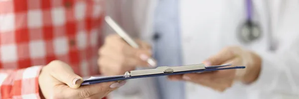 Läkare visar patienten urklipp med dokument i kliniken närbild — Stockfoto