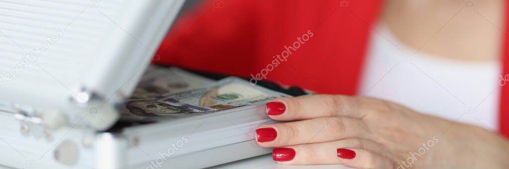 Satisfied woman opening suitcase full of money closeup