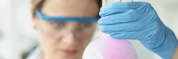 Mujer científica sosteniendo frasco con líquido púrpura con espuma en laboratorio — Foto de Stock