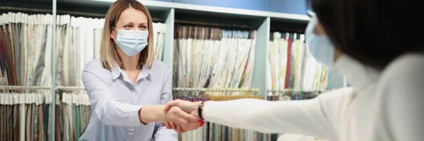 Acheteur et vendeur de masques médicaux de protection serrent la main dans le salon de tissus — Photo