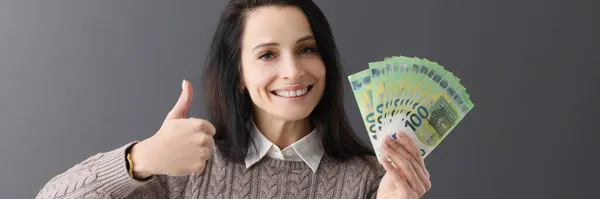 Χαμογελαστή γυναίκα κρατά τους αντίχειρες και εκατό ευρώ χαρτονομίσματα — Φωτογραφία Αρχείου