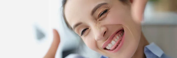 Feliz mulher sorridente faz moldura de fotos com as mãos — Fotografia de Stock