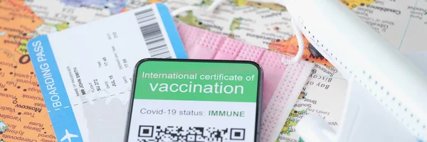 Paszport szczepień COVID-19 jest wyświetlany na smartfonie obok biletu lotniczego — Zdjęcie stockowe