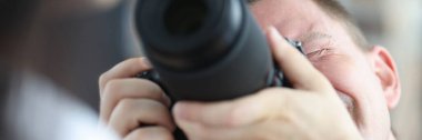 Siyah profesyonel kamera kullanan bir adam kadının fotoğrafını çekiyor.