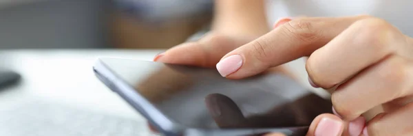 La ragazza preme il dito sullo schermo dello smartphone sul tavolo è il computer portatile — Foto Stock