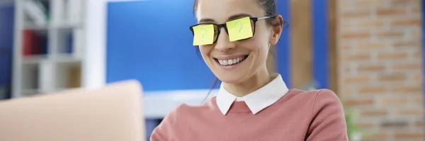 Giovane donna sorridente con stickars giallo su occhiali con punto interrogativo funziona sul computer portatile — Foto Stock