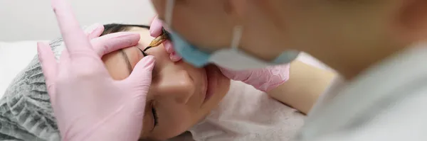 Vrouw schoonheidsspecialiste maakt permanente oog tatoeage voor klant closeup — Stockfoto
