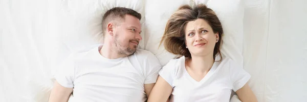 Mujer frustrada se encuentra en la cama con el hombre sonriente primer plano —  Fotos de Stock
