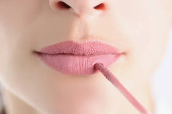 Női ajkak rózsaszín rúzzsal és ecsettel közelkép — Stock Fotó