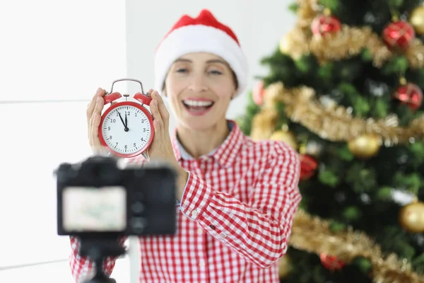 Joyful vrouw blogger schiet video op camera met wekker op de achtergrond van Nieuwjaar boom — Stockfoto