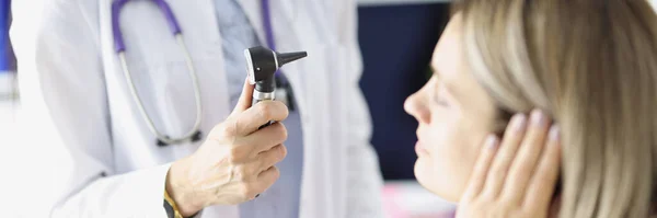 Otorrinolaringólogo examina una oreja mujer con otoscopio — Foto de Stock