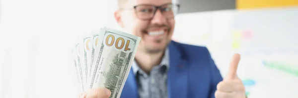 Smiling businessman holding cash and thumbs up gesture — Stock Photo, Image