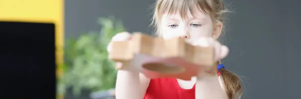 Little girl folds wooden gears on table — Stockfoto