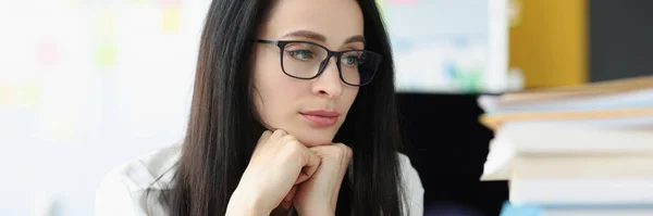 Sad businesswoman looks at large stack of folders with documents at workplace — стоковое фото