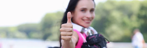 Mosolygó nő görgők a vállán mutatja hüvelykujj up közelkép — Stock Fotó