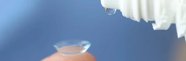 Gotas transparentes pingando da garrafa para o close-up da lente de contato — Fotografia de Stock