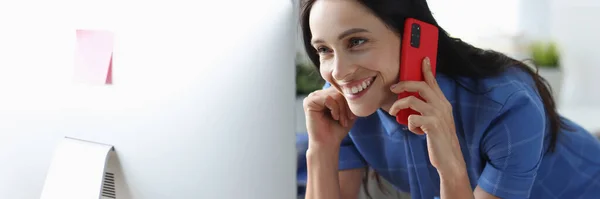 Fröhliche Frau spricht auf Handy und blickt auf Computerbildschirm — Stockfoto