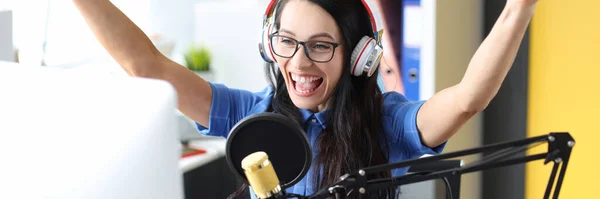 Mulher sorridente em fones de ouvido se alegrando na frente do microfone na estação de rádio — Fotografia de Stock