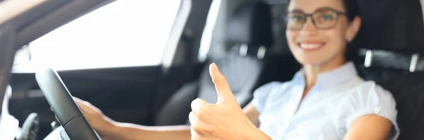 Woman sitting behind wheel of car and showing thumb up closeup — Stock Photo, Image