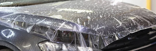 Película de vinilo de poliuretano pegada en la capucha del primer plano del coche — Foto de Stock