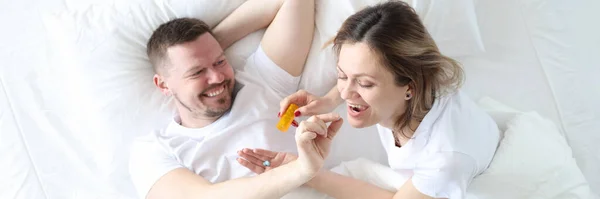 Hombre da a la mujer una píldora anticonceptiva en la cama — Foto de Stock