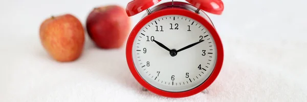 Red alarm clock standing on white towel near apple closeup — Stock Photo, Image