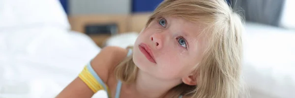 Mała dziewczynka leży w łóżku w klinice i płacze — Zdjęcie stockowe