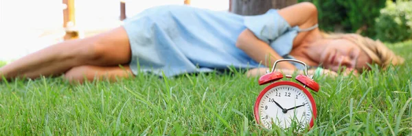 Женщина спит на траве возле будильника — стоковое фото