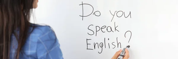 Vrouw leraar schrijft met marker spreek je Engels op wit bord — Stockfoto