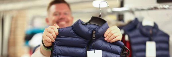Smiling man holding new warm vest in store closeup — Stock Photo, Image
