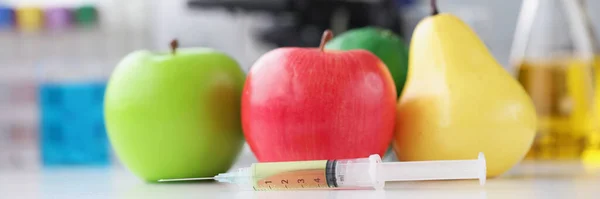 Seringa com medicamentos que se encontram perto de frutas no fundo do microscópio close-up — Fotografia de Stock