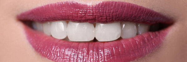 Closeup of woman smile with burgundy lips painted with lipstick