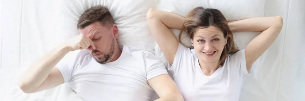 침대에 누워 있는 부부. 사람 이손으로 코를 막고 있다 — 스톡 사진