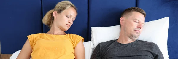 Уставшие мужчина и женщина спят в постели с ноутбуками крупным планом — стоковое фото
