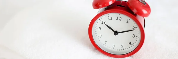 Red alarm clock stands on white towel closeup — Stock Photo, Image