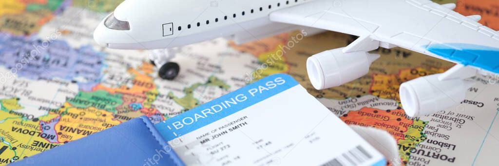 Passport plane ticket and toy plane stands on world map closeup